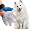 hand pulling fur from blue deshedding glove while furry white dog watches